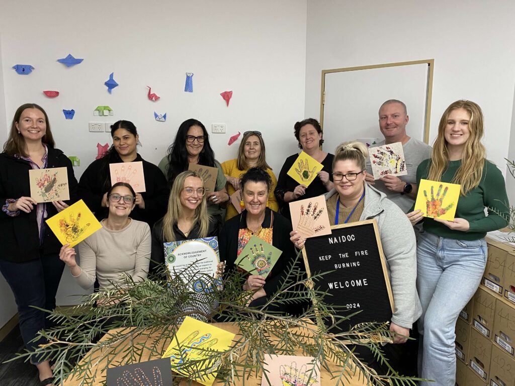 staff members holding NAIDOC artworks