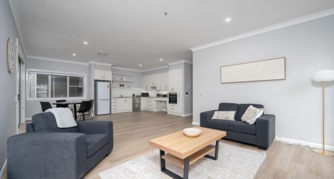 open plan living area of SDA apartment viewed across living, dining and kitchen